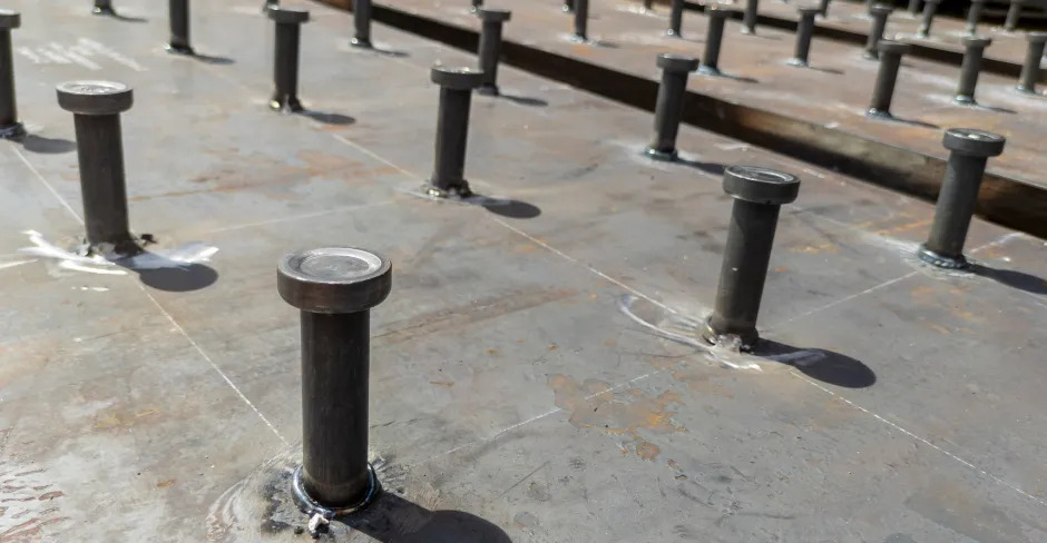 Rows of arc weld studs securely attached to a metal plate, showcasing precision in industrial welding.